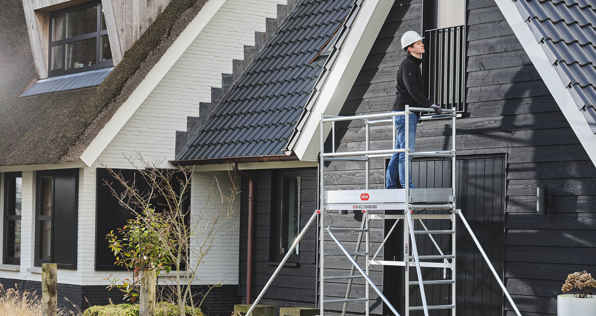 Man werkt op een kamersteiger aan de gevel van een woning in Assen, Groningen of Drenthe